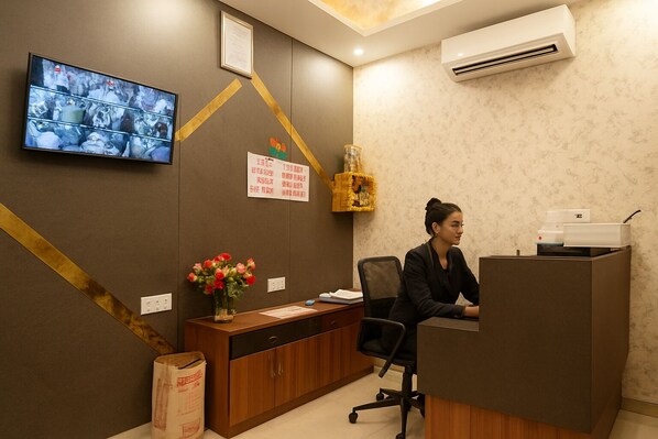 A reception desk with a television, a vase of flowers, and a bulletin board with notices.
