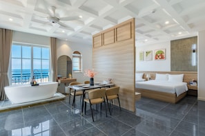 A modern hotel room with a bathtub, dining area, and a bed. - Amaris Sunset Hotel (Phu Quoc)