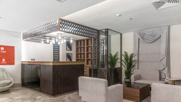 A modern lobby with a reception desk, seating area, and a decorative partition.