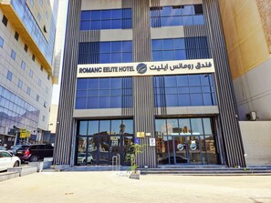 A hotel with a modern facade, large windows, and a sign indicating it is the Romanc Elite Hotel. - Romance Elite Hotel (Makkah)