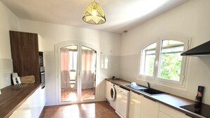A kitchen with a washing machine, a sink, and a window. - LES AGRUMES (Lucciana)