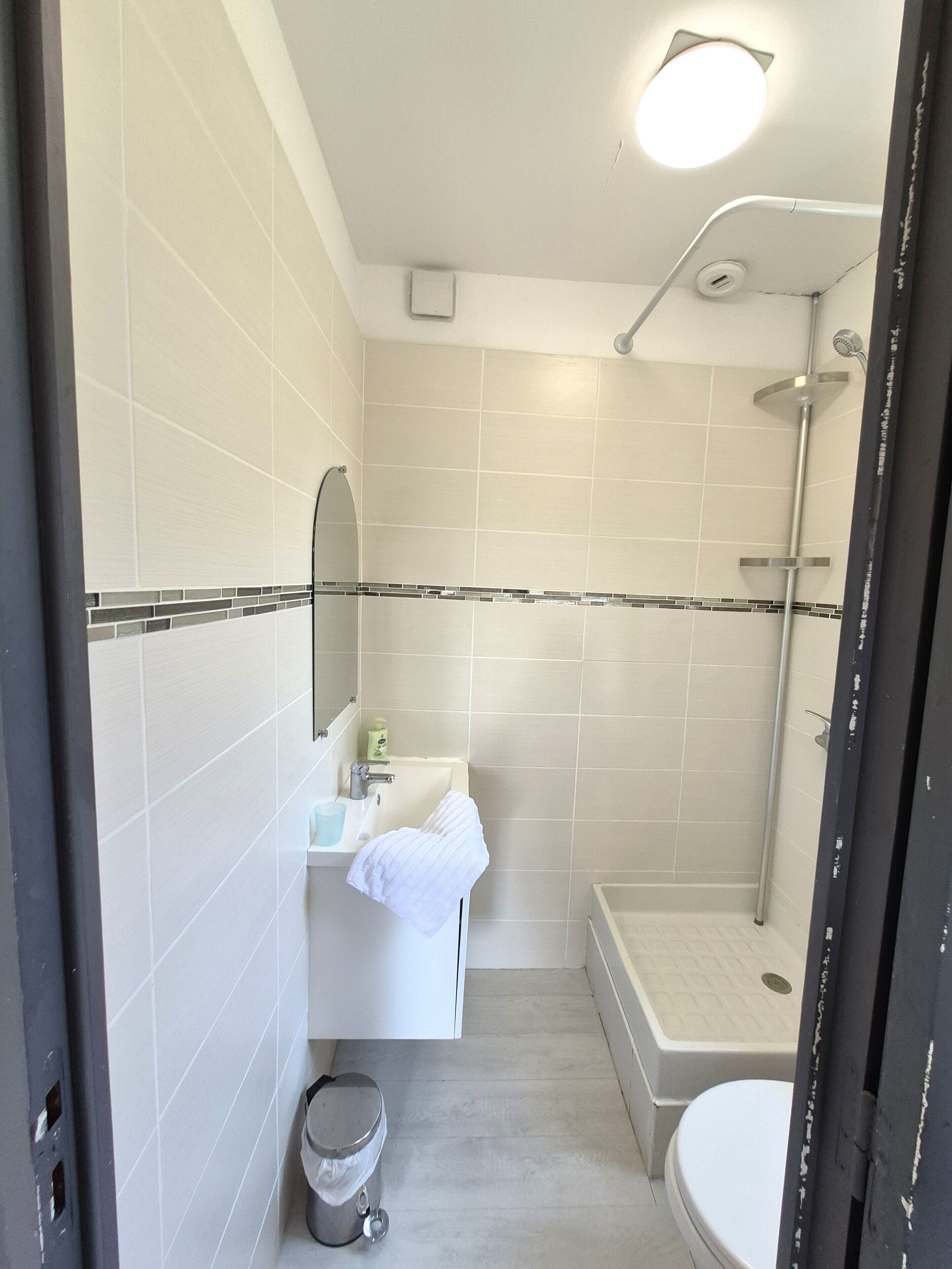 Une salle de bain équipée d’un lavabo, d’un miroir, d’un porte-serviettes, de toilettes et d’une douche.