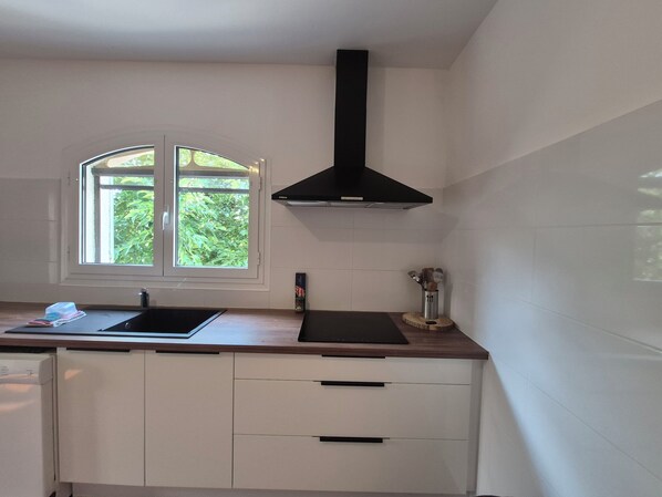 A kitchen with a window, a black range hood, a sink, and a countertop.