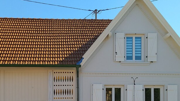 A two-story house with a tiled roof, white exterior walls, and a garage door. - Cosy gîte in renovated farmhouse. Spacious bedroom + living room. Pets allowed (Weitbruch)