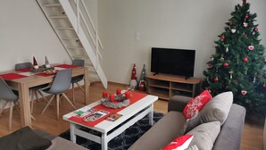 A living room with a staircase, a dining area, a sofa, and a Christmas tree. - Cosy gîte in renovated farmhouse. Spacious bedroom + living room. Pets allowed (Weitbruch)