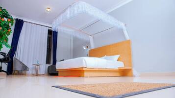 Una habitación de hotel moderna con una cama, una mesita, una silla y una planta decorativa.