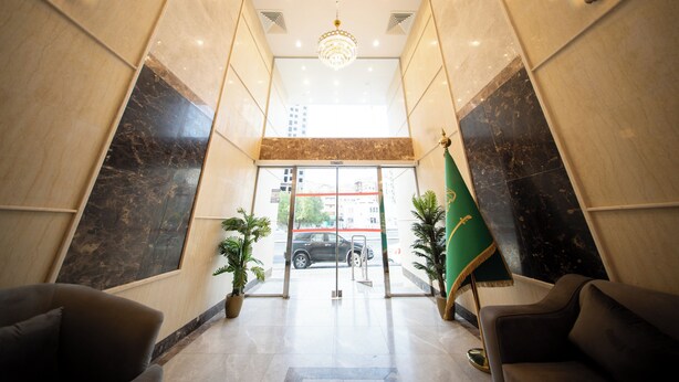 A hotel lobby with marble walls, a chandelier, and a flag. - Rayhanat Almakan Hotel (Makkah)