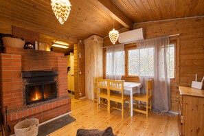 Ein gemütliches Blockhaus-Interieur mit Kamin, Holzmöbeln und großen Fenstern.