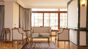 A spacious living room with a large window, a sofa, two armchairs, a coffee table, and a patterned rug. - Kennah Lascaic | 3BR Near Korba & Metro, Heliopolis (Cairo)