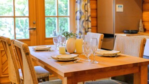 A wooden dining table set with plates, glasses, and a vase.