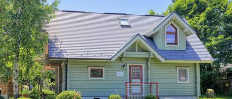 A small, single-story house with a gabled roof, a front porch, and a picnic table in the yard.
