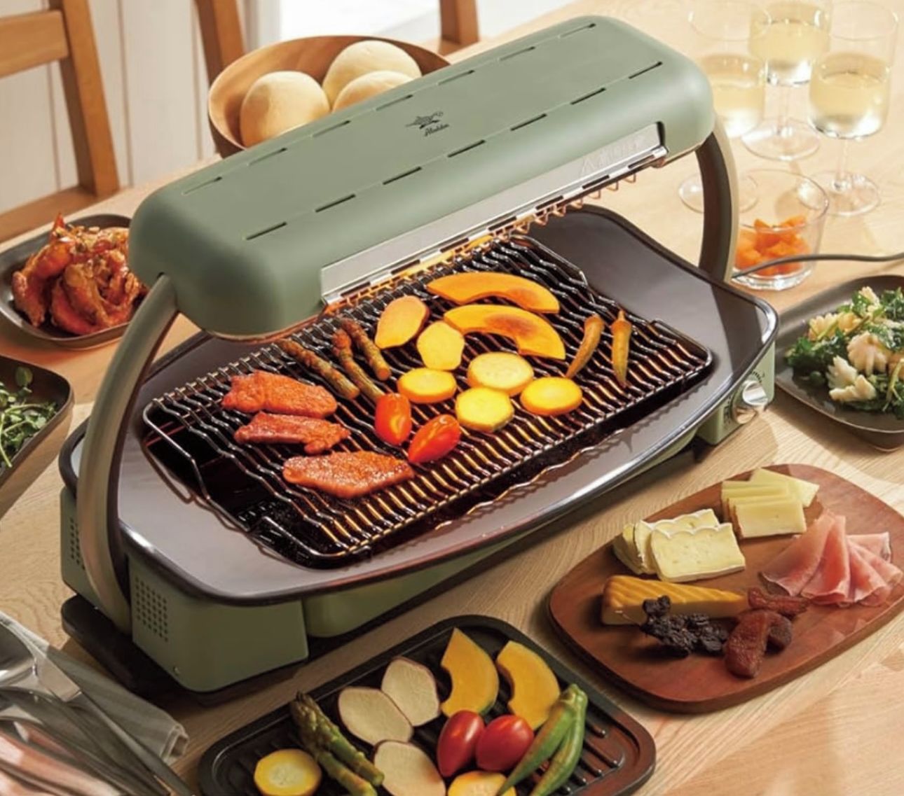 A portable grill with various meats and vegetables being cooked.