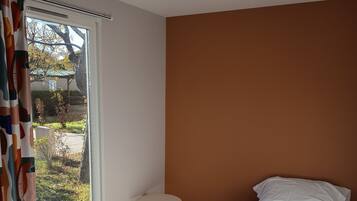 Un dormitorio con cama, una mesita auxiliar y una ventana con cortinas.