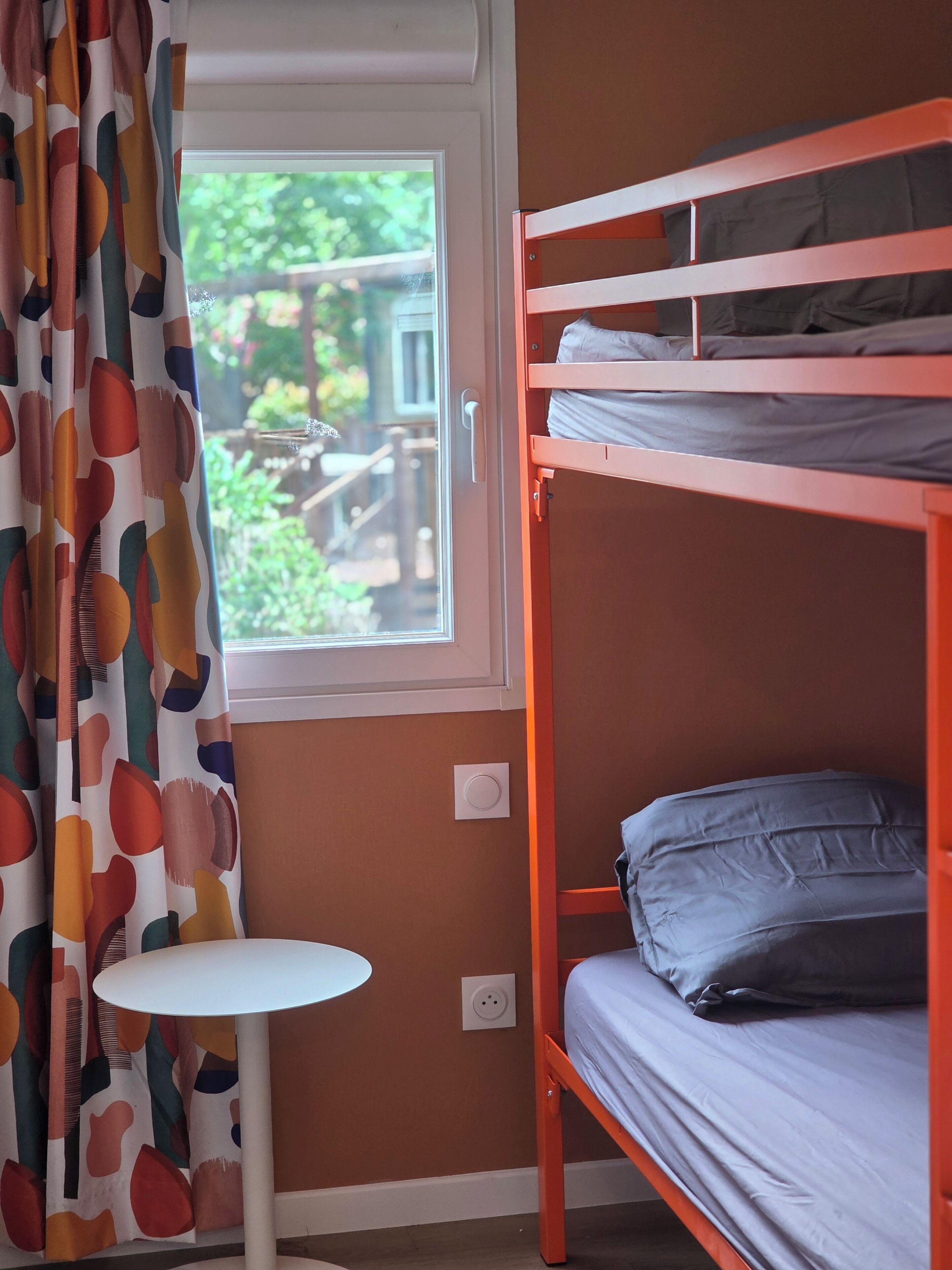 A bunk bed with a small table and a window with curtains.
