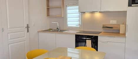 A modern kitchen with white cabinets, a yellow dining table, and matching chairs.