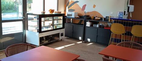 Un restaurante con vigas de madera, ventanas amplias y coloridos adornos en las paredes. Mesas y sillas dispuestas para comer.
