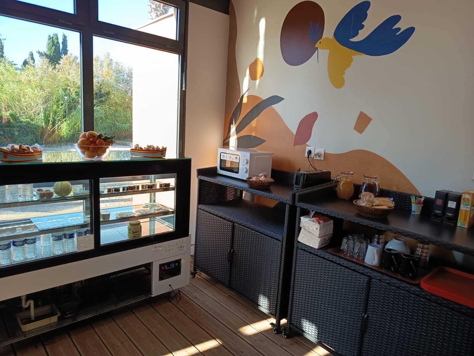 Una cocina con un ventanal grande, un microondas y varios alimentos en estantes.