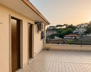 Un balcon doté d’un sol carrelé, de deux portes en bois et d’un appareil de climatisation.