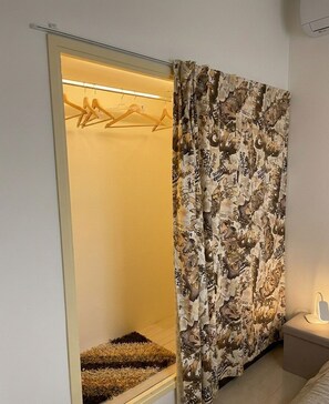 Une pièce dotée d’un dressing comprenant un miroir, une tringle à vêtements et un petit tapis.