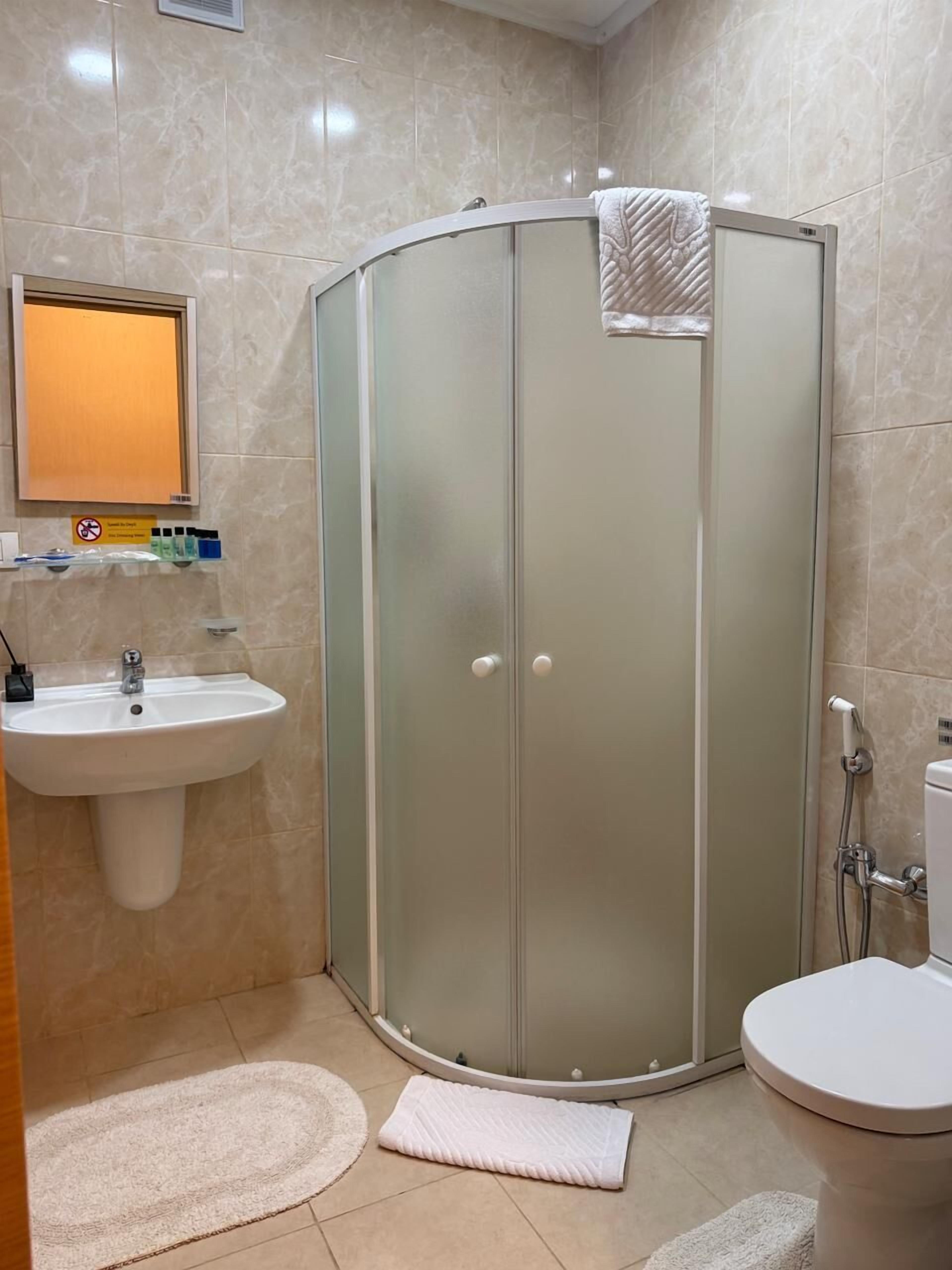 A bathroom with a glass-enclosed shower, a sink, a toilet, and a mirror.