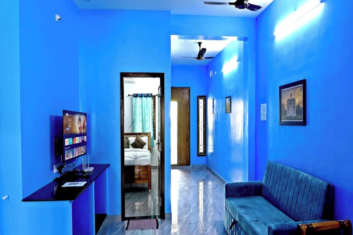 A hallway with blue walls, a bed, a desk, a sofa, and ceiling fans.