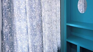 A room with a blue wall and a curtain with a floral pattern. - Golden Home Stay (Puducherry)