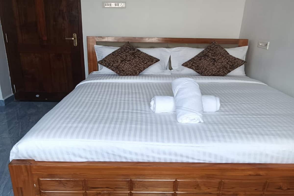 A neatly made bed with a wooden headboard, two pillows, and rolled towels.