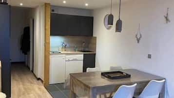A modern kitchen with dark cabinets, a wooden dining table, and white chairs.