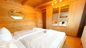 A wooden-paneled room with a bed, a mirror, and a wardrobe.