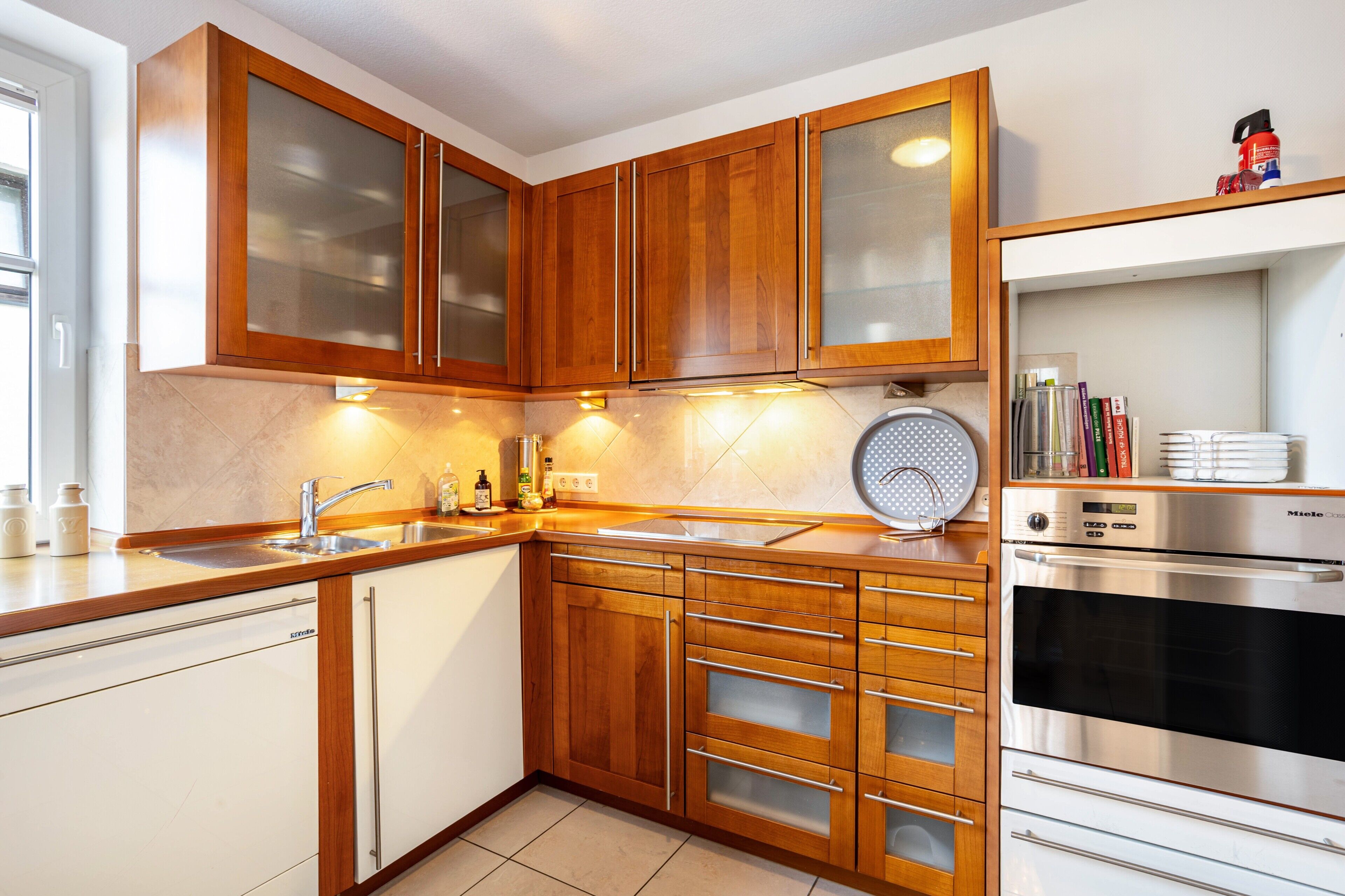 Een moderne keuken met houten kastjes, een inbouwoven en een magnetron.