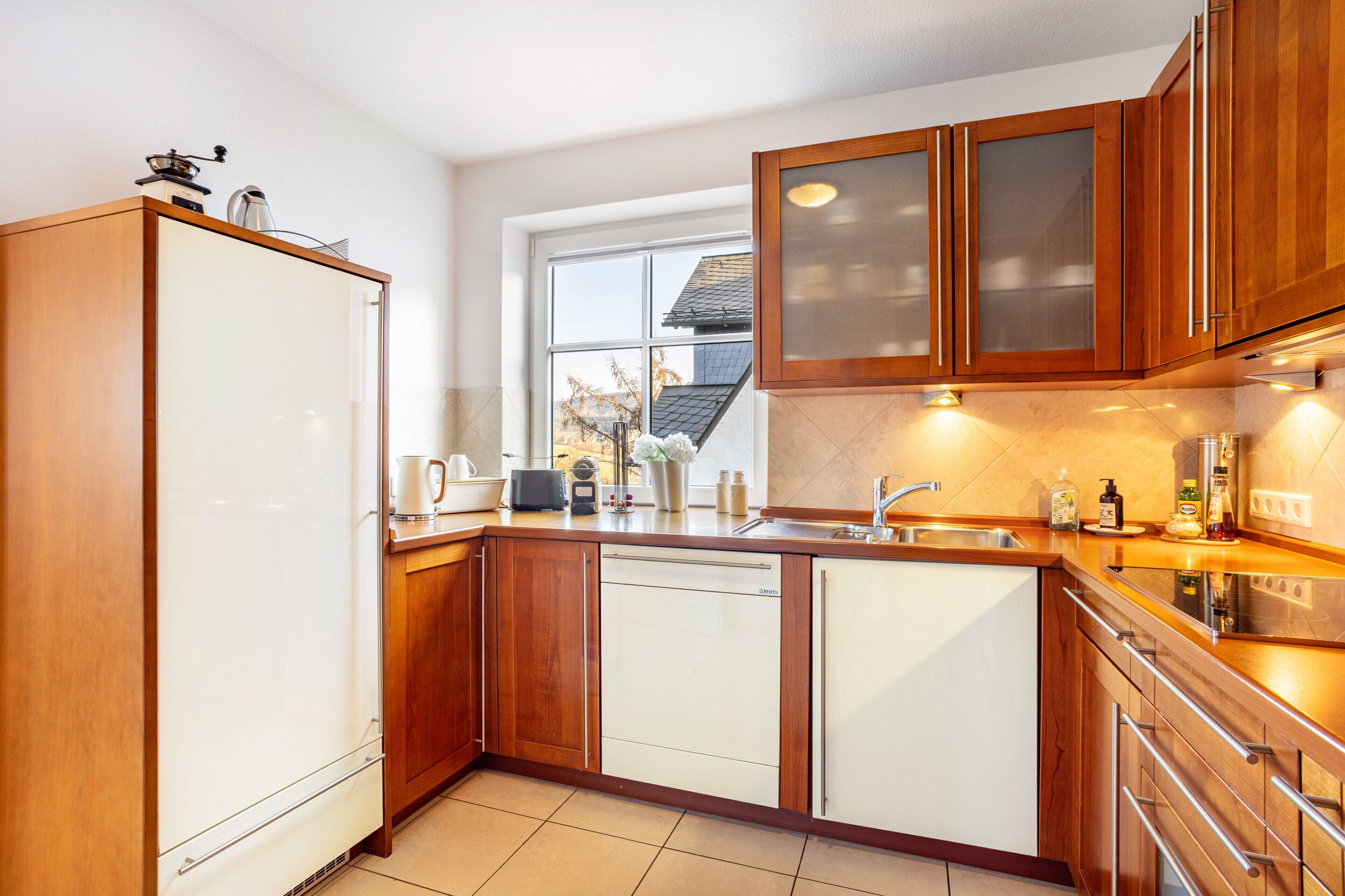 A kitchen with wooden cabinets, a dishwasher, a sink, and a window.