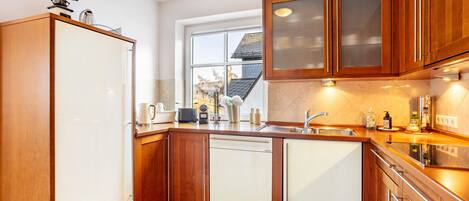 A kitchen with wooden cabinets, a dishwasher, a sink, and a window.