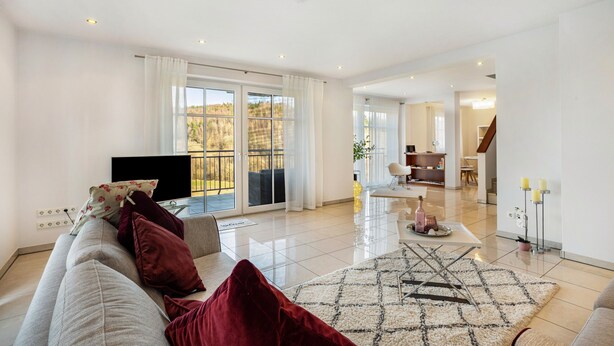 A modern living room with a sofa, TV, and a view to the outside.