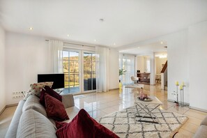 A modern living room with a sofa, TV, and a view to the outside.