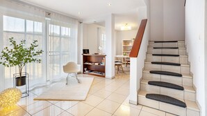 A modern interior with a staircase, a dining area, and a bookshelf.