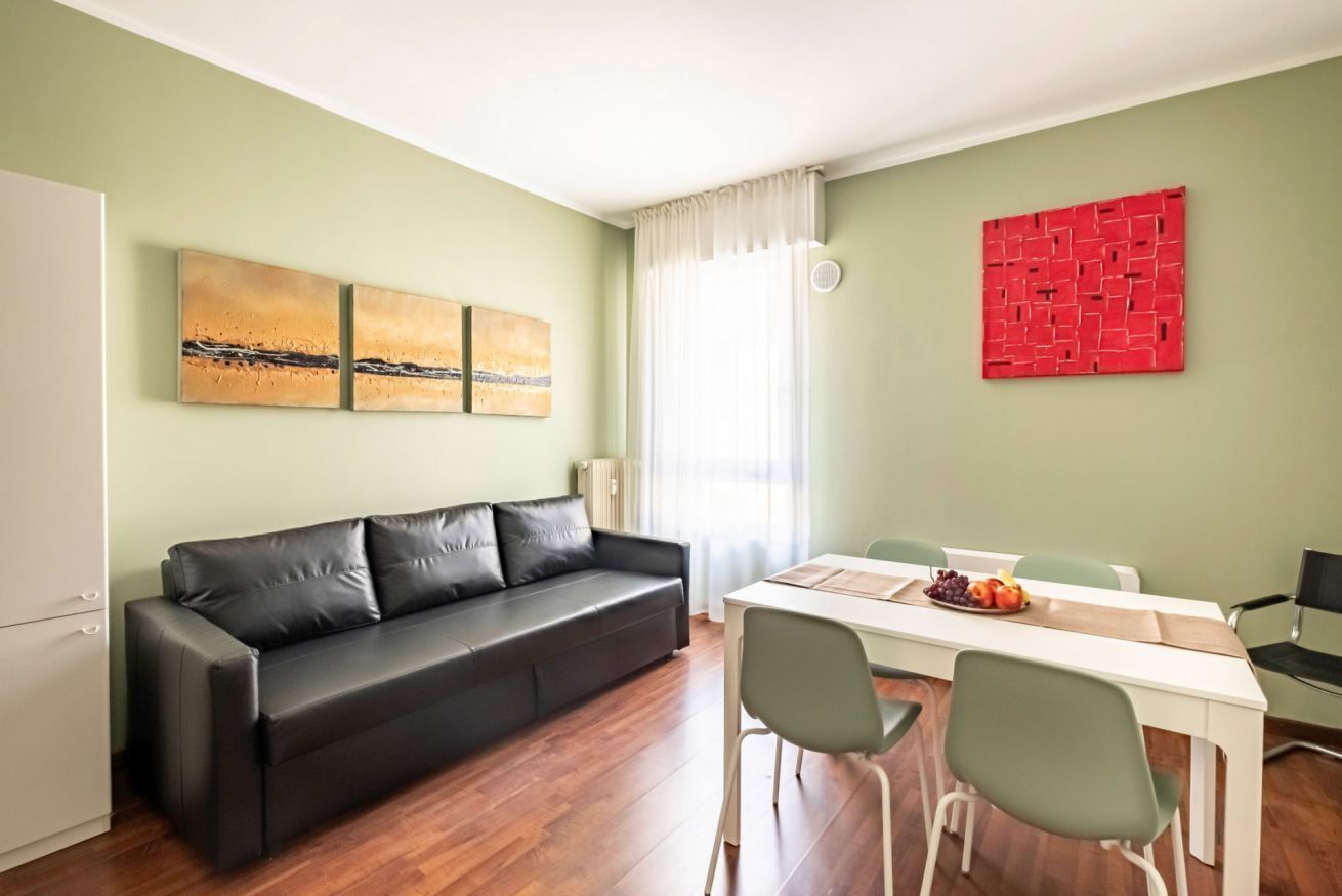 Un soggiorno moderno con un divano in pelle nera, un tavolo da pranzo con sedie e opere d'arte alle pareti.