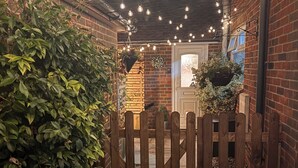 A brick building with a wooden gate, a brick wall, and a door with a window. - Warm & Stylish Cottage in Historic Odiham (Odiham)