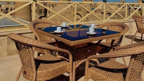 Terraza en la azotea con mobiliario de mimbre y vistas a edificios históricos, incluyendo una torre y una cúpula.