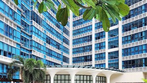 A modern building with a large pool surrounded by lush greenery.