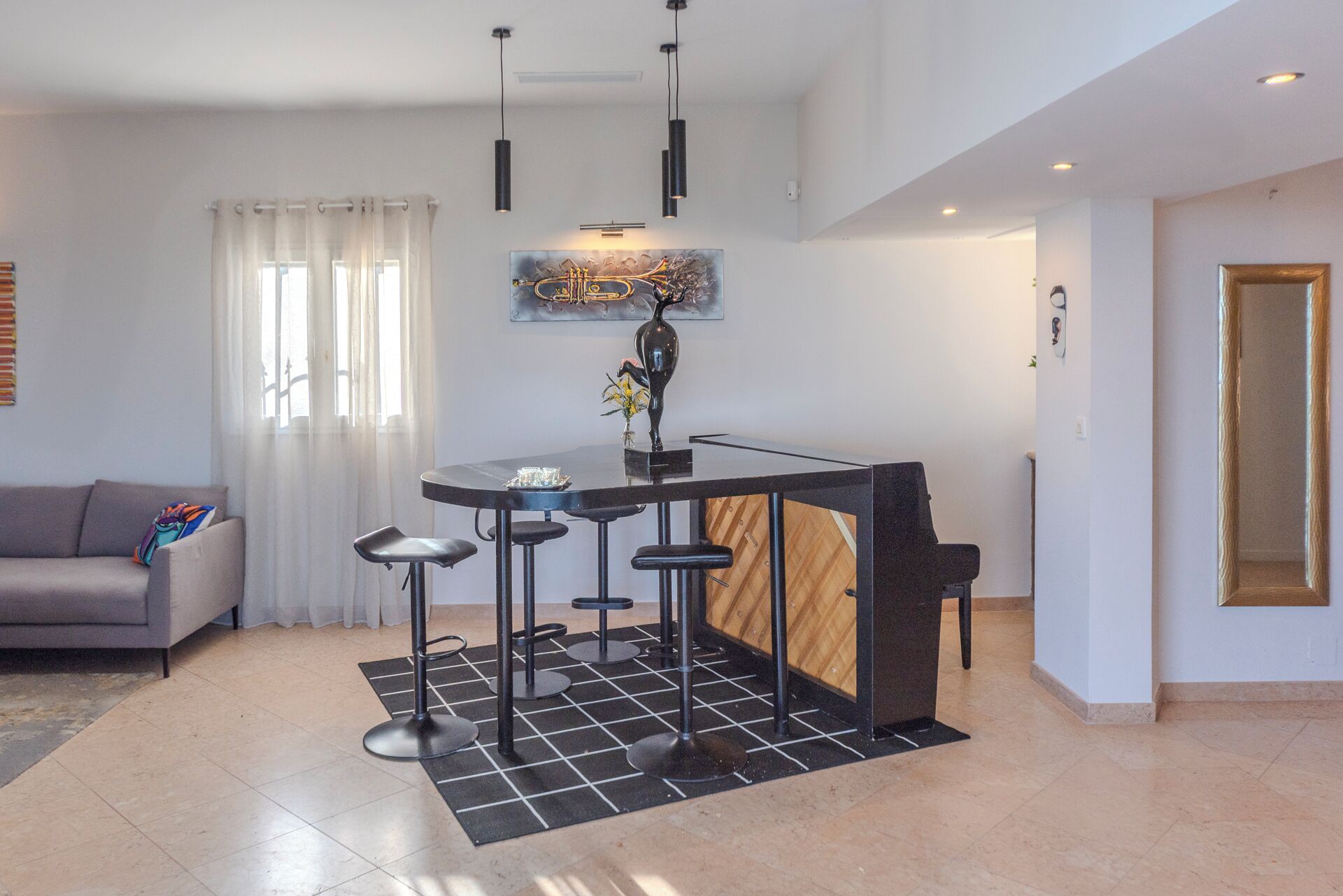 A modern kitchen with a central island, bar stools, and pendant lighting.