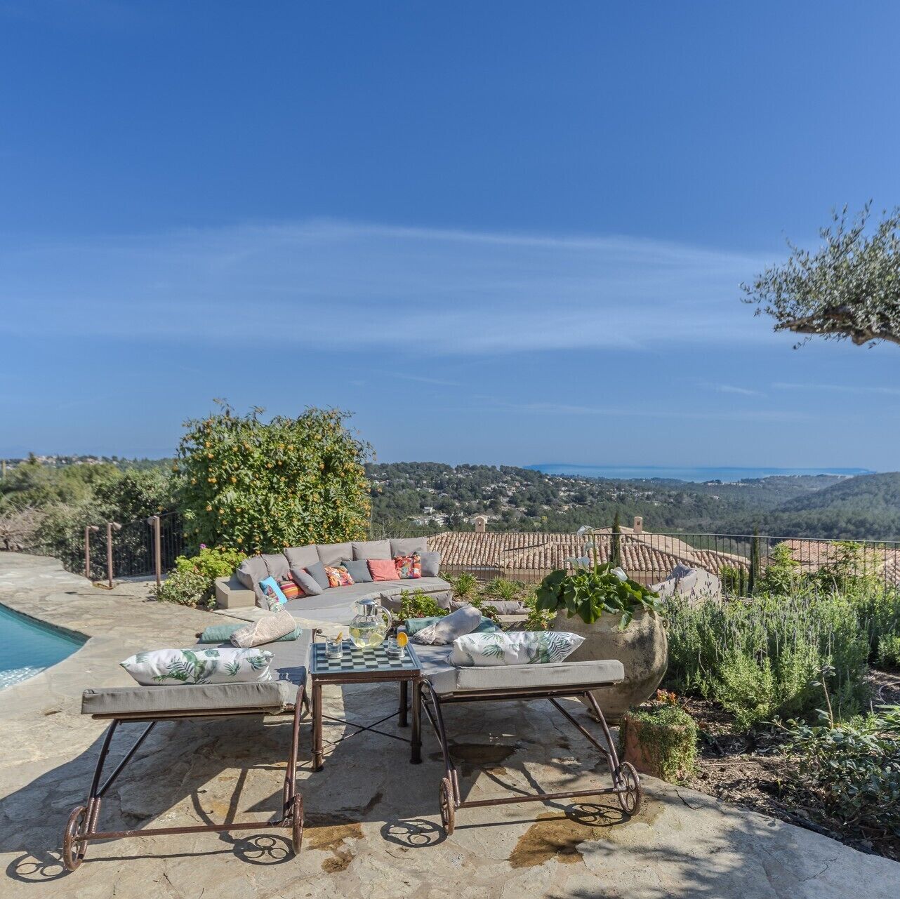 A patio with a sofa and two chairs, a small table, and a view of the countryside.