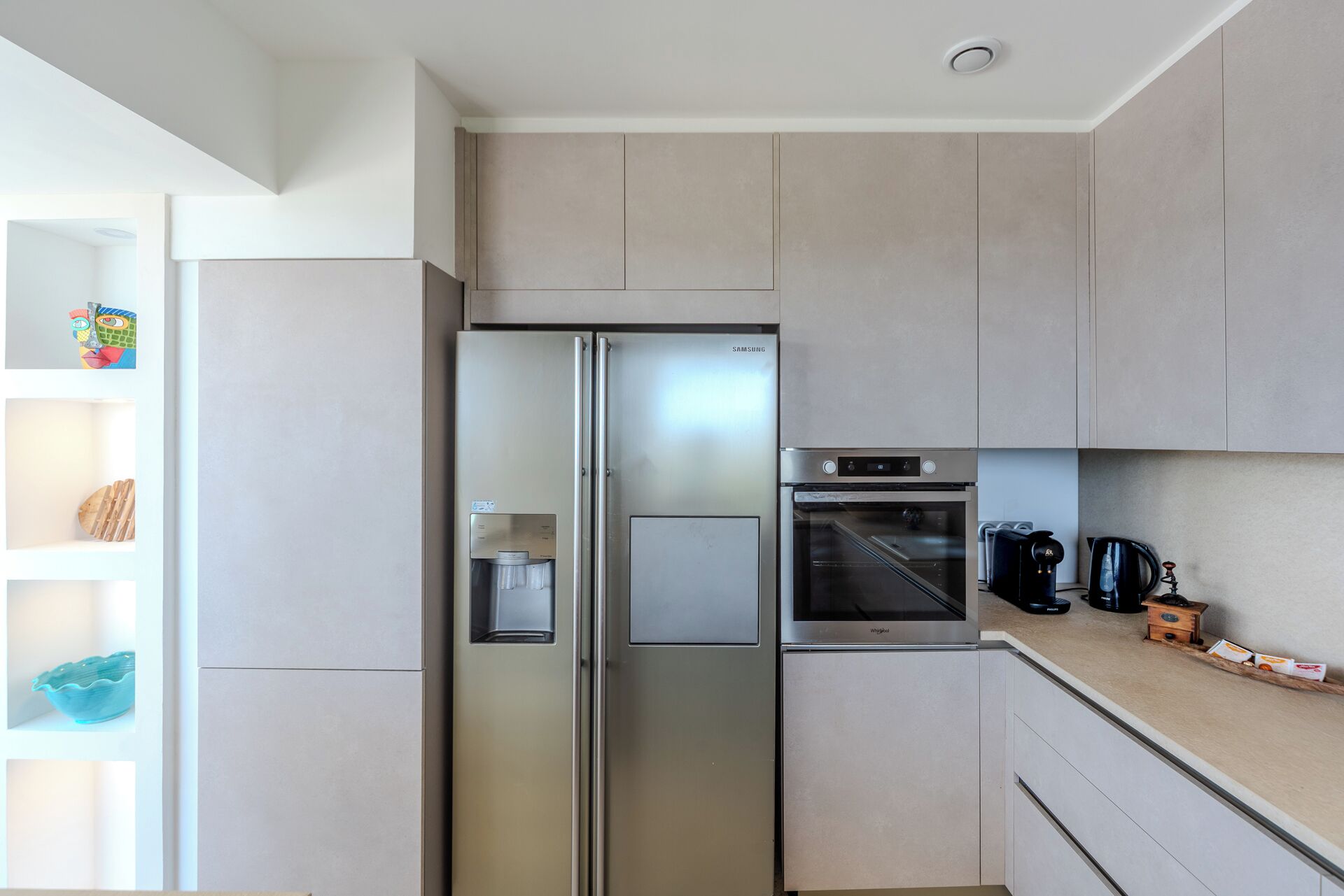 A modern kitchen with a stainless steel refrigerator, built-in oven, and a coffee maker on the countertop.