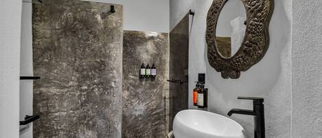 A bathroom with a white sink, black faucet, and a shower with a marble wall.