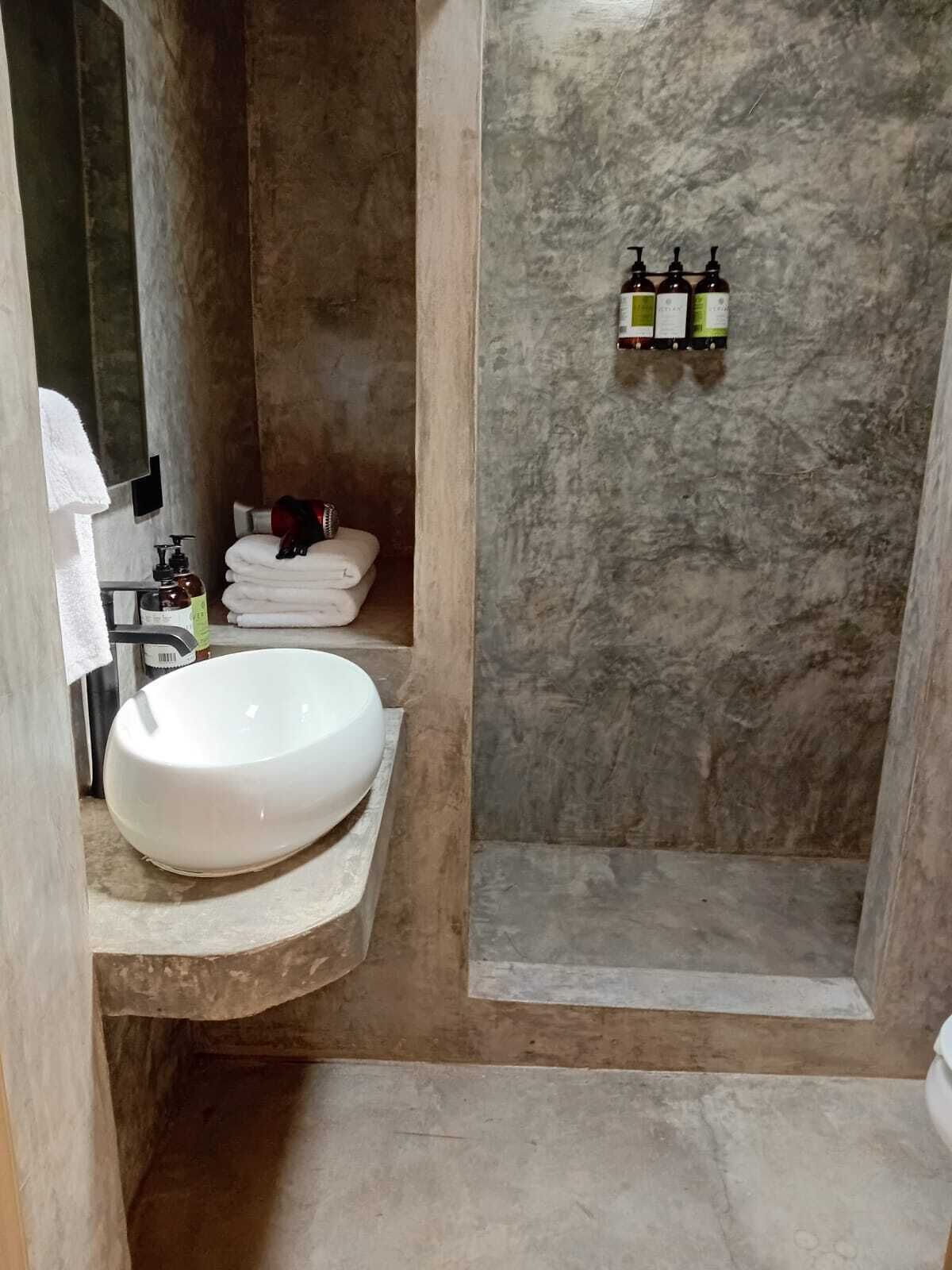 A bathroom with a white sink, a towel rack, and a shower area with a textured wall.