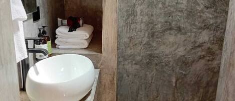 A bathroom with a white sink, a towel rack, and a shower area with a textured wall.