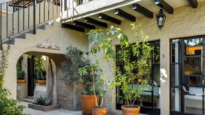 Un patio con plantas en macetas, una escalera y la entrada de un edificio.