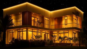A modern two-story house with large windows and a warm yellow exterior lighting. - Swagatha The Beach House ECR (Kanchipuram District,ECR 603104)