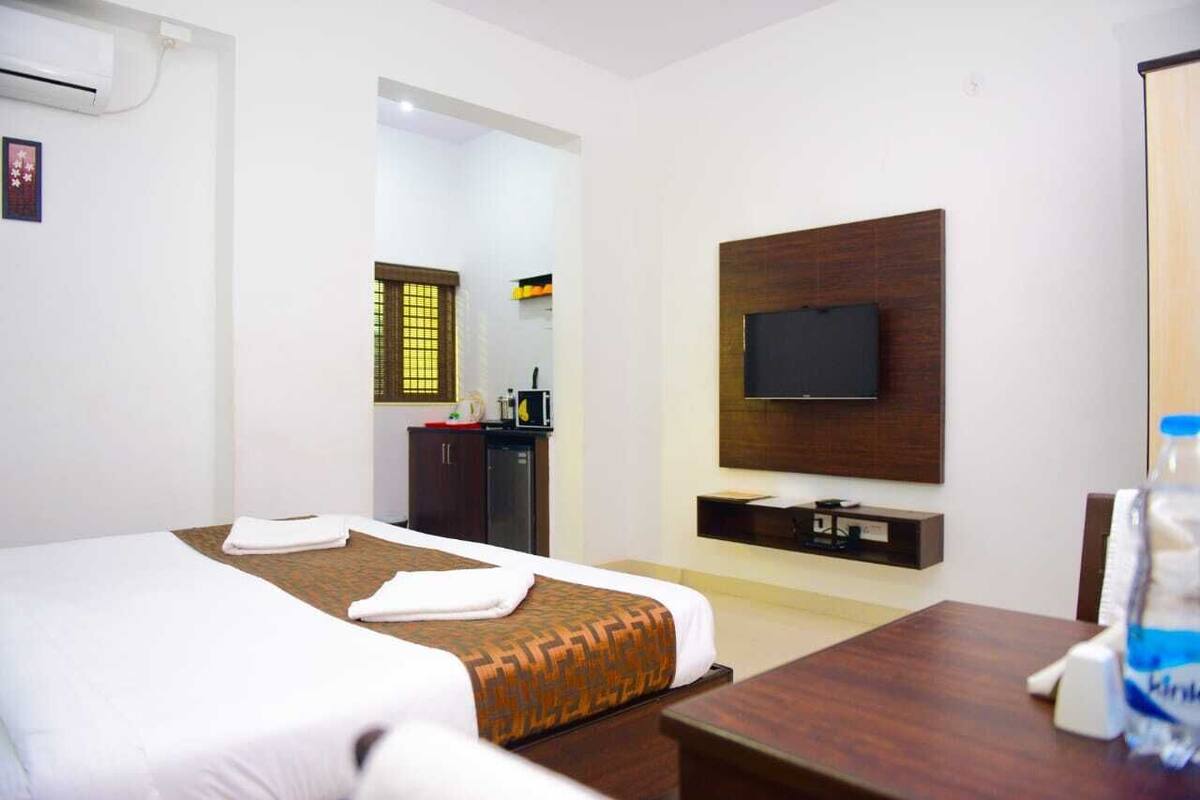 A hotel room with a large bed, a TV mounted on the wall, a desk, and a wardrobe.