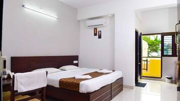 A hotel room with a bed, bedside tables, an air conditioning unit, and a view of the outside.
