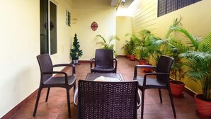 A patio area with wicker furniture, potted plants, and a tiled floor. - VARSHA ENCLAVE TRINITY HOUSE (Mysore)